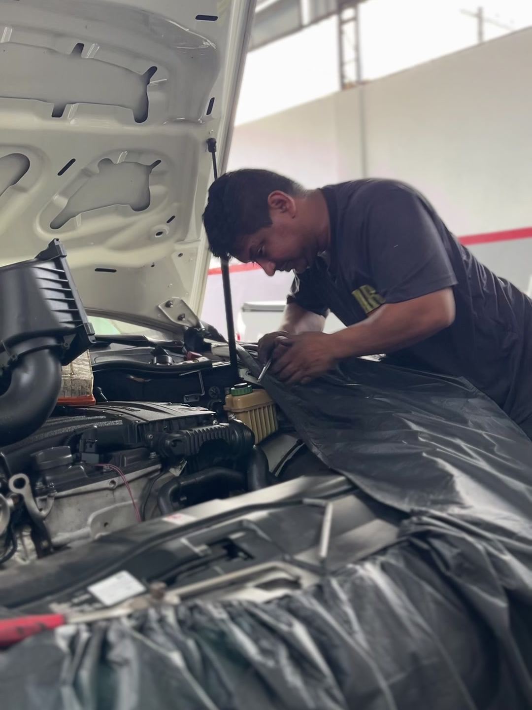 Profissional da Flex Norte trabalhando no sistema de ar-condicionado sob o capô de um veículo